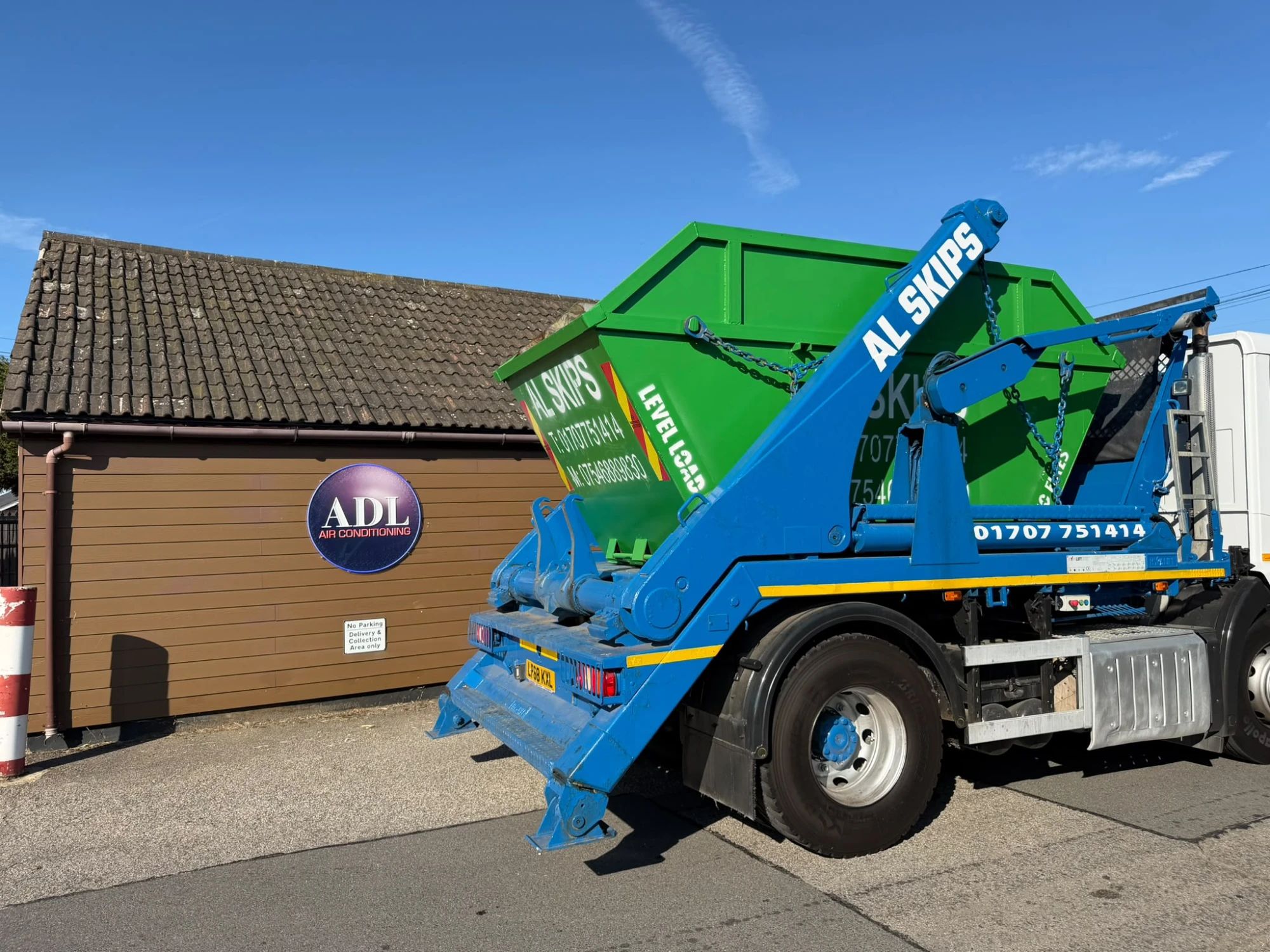 Green AL Skips skip loaded on the blue AL Skips skip lorry